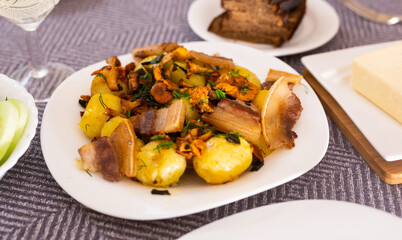 traditional rustic dish. fried potatoes with chanterelle mushrooms and pork brisket with herbs