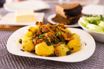 baked  potatoes with chanterelles, served with herbs on white plate