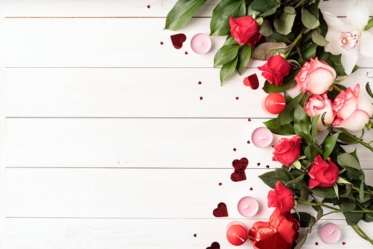 red roses and valentine's day decorations top view on white wooden background