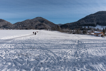 Fototapeta na wymiar Spuren im Schnee mit Bergen im Hintergrund im Winter mit Personen