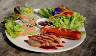 Steak pork, fried sausages, salad roll with barbecue sauce on plate