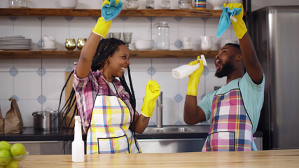 Young african family couple doing cleaning in kitchen
