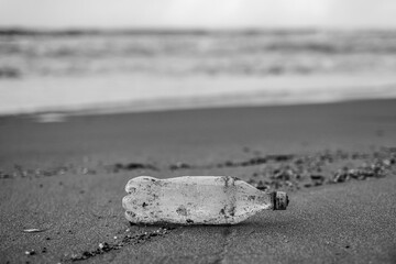 Black and white view of Plastic bottle waste abbandoned on sea coast ecosystem,environmental pollution concept