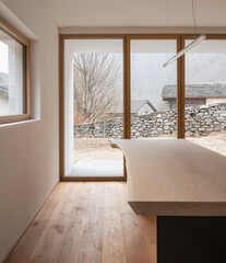 Detail of wooden table with design lamp and window to the forest of the Swiss Alps.  Nobody inside