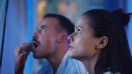 Naklejka premium Close up of couple eating popcorn and watching tv with noise on screen at home