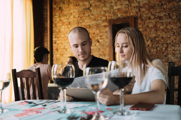 Young adorable couple reading the menu in a restaurant - A couple of smiling Caucasians looking at and choosing the food on the menu..