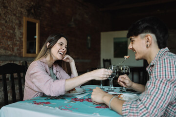 Lovely girl feeding her boyfriend on romantic dinner - Beautiful woman sharing a delicious meal with her boyfriend in a restaurant.