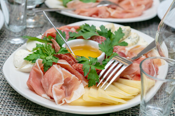 Close up of italian antipasto - assorted plate with cheese, ham, prosciutto and honey. Mediterranean appetizer