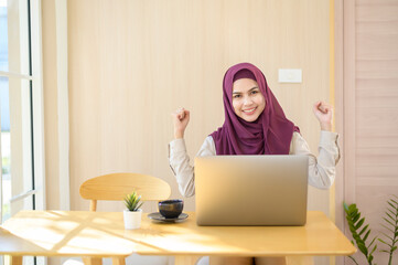 Muslim business woman wearing hijab working with her laptop in coffee shop