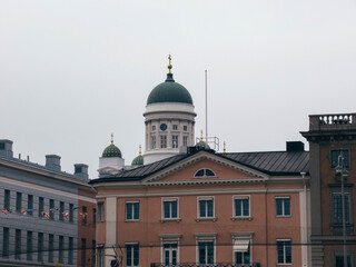 Fototapeta na wymiar Helsinki Cathedral behind colorful buildings on a cloudy day. 