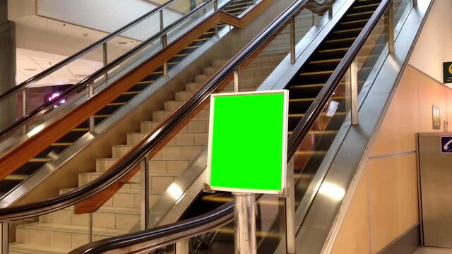One side of the YVR airport with green billboard beside escalator.
