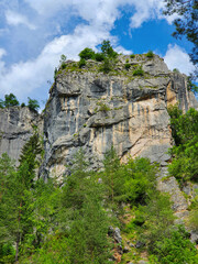 Fototapeta na wymiar VERTICAL: Breathtaking cliffs tower above a forest in the Austrian mountains.