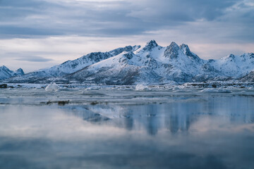 Fototapeta na wymiar Snowy mountains on seashore with glaciers at sunset