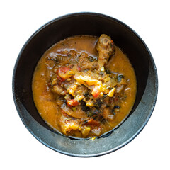 top view of Chakhokhbili (traditional georgian dish from stewed chicken meat, tomato, eggplant and fresh herbs) in black bowl cutout on white background