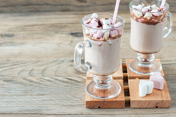 Hot cocoa or chocolate drink with marshmallow in glass mug on wooden table. Concept of cosy Christmas and New Year holidays, copy space