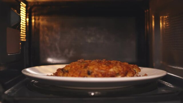 Plate with food spinning and warming in microwave oven