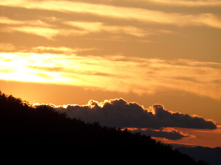 Orangener Himmel mit dunklen Bergen und Sonnenuntergang und festen Wolken. Sonnenuntergang in der Toskana in Italien.