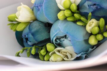 Luxurious wedding bouquet of blue peonies and white freesias in white kraft paper close-up. Beautiful spring flowers. High quality photo