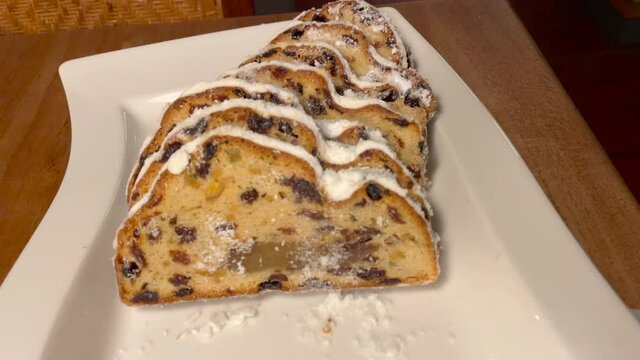 Zoom out shot of german christmas fruit cake named Stollen served on white plate, close up.