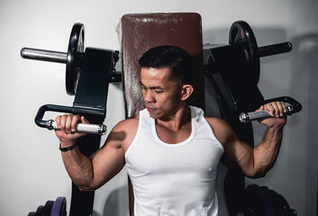 A fit asian man prepares to do machine shoulder presses. Shoulder workout demonstration.