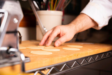 Fototapeta na wymiar Making Pasta and Tortellini at Home on Wooden Rack and Chrome Pasta Maker