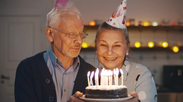 Happy senior couple celebrating anniversary or wife birthday at home
