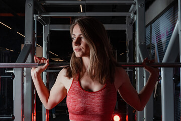 Beautiful young fitness woman doing squats with a barbell on the Smith Machine in the gym. Beautiful woman poses for the camera.