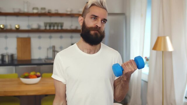 Hipster weak guy doing fitness training with dumbbells at home