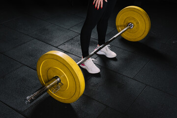 Fototapeta na wymiar Young beautiful athletic woman poses with barbells in the gym. The woman prepared to do deadlift poses for the camera.