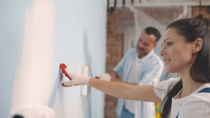 Young happy couple repairing and painting wall at home - Powered by Adobe