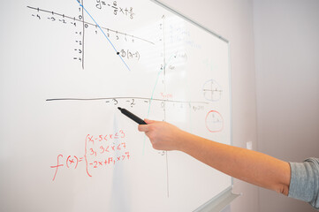 A person, presenter pointing with a marker in the hand during the presentation to data displayed on the whiteboard.