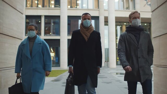 Business people in medical masks walking to office outdoors