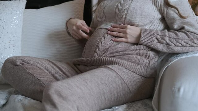 close-up of a pregnant woman stroking and playing with her belly