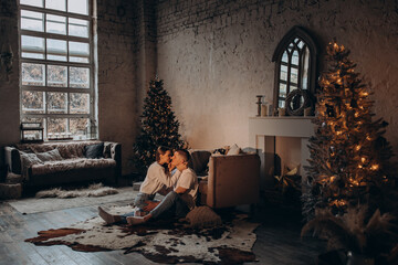 Fototapeta na wymiar The guy and the girl celebrate the New Year. A loving couple have fun on Christmas in a cozy studio setting. New Year's love story.