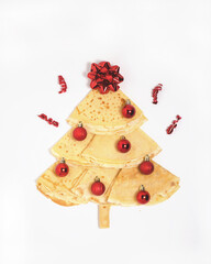 Christmas tree made of pancakes with red ornaments and red bow at the top of the tree celebrating