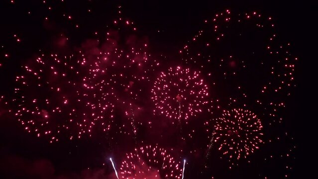 Bright red fireworks explode in the night sky.