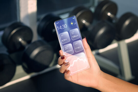 Transparent Smartphone. The Woman Use a futuristic design phone in a fitness gym . future technology and business concept . 