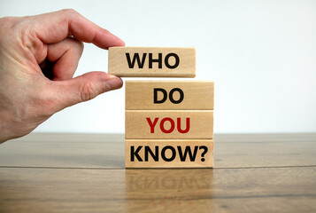 Who do you know symbol. Male hand. Wooden blocks with words 'who do you know'. Beautiful wooden table, white background. Business and who do you know concept. Copy space.