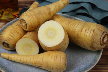 Close up of group raw isolated sliced parsnip root vegetables on blue china plate