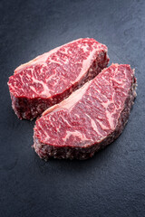 Rohes dry aged Wagyu Roastbeef Steak angeboten als close-up auf einem schwarzen Board mit Textfreiraum