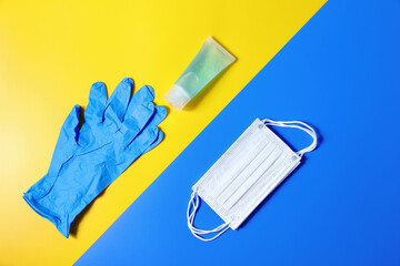 Top view flat lay yellow and blue background with gloves, a Medical mask, and gel alcohol.
