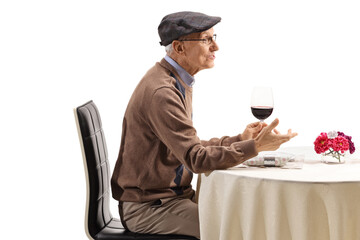 Elderly man with a glass of wine at a restaurant table