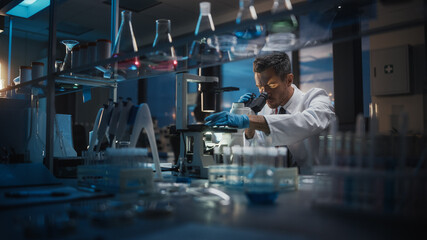 Medical Development Laboratory: Scientist Looking Under Microscope, Analyzes Petri Dish Sample. Pharmaceutical Lab with Specialists Conducting Medicine, Biotechnology Research. Evening Work