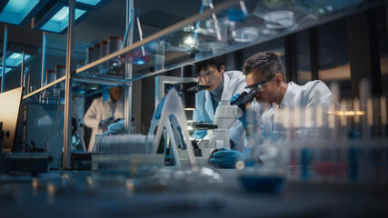 Modern Medical Research Laboratory: Team of East Asian and Caucasian Scientists Work on Laptop, do...