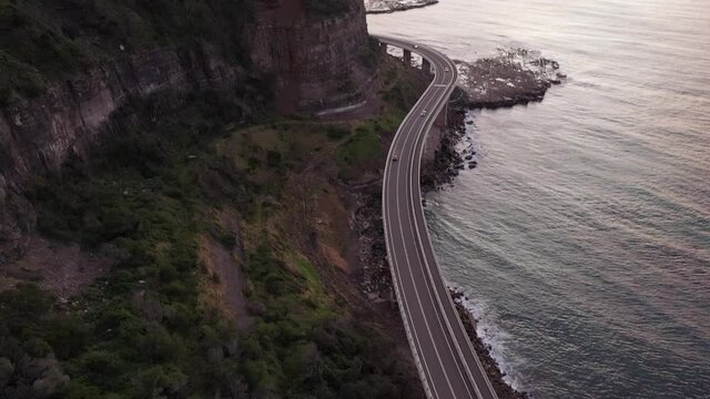 Drone shot reveal of the sunrise and ocean during golden hour with mountain terrain. Shot in Wollongong - Australia