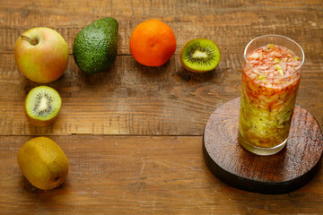 Glass of kiwi apple cocktail smoothie on a wooden table near kiwi apple avocado