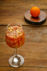 Glass of fresh kiwi apple smoothie on a wooden table next to a tangerine stand.