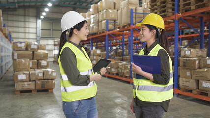 Two warehouse female managers in protective workwear organizing distribution in warehouse storage...