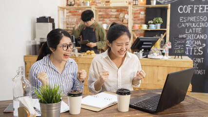 happy college student girls celebrate successful teamwork results in cafe bar. excited two asian...