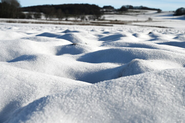 Close-up of a snow covered field. The snow looks like white sand dunes.